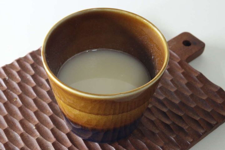 木製のカッティングボードの上に置かれた、茶色のカップに入った完成したポタージュスープ