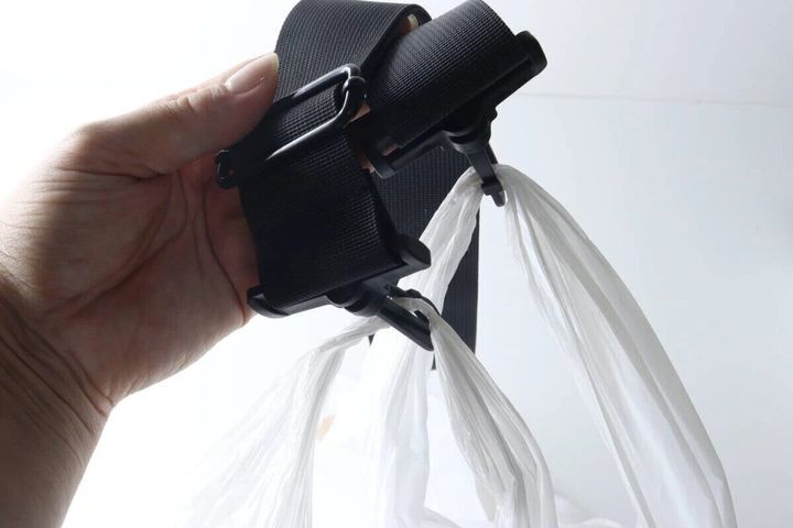 黒いストラップのフックに白いビニール袋の持ち手を複数かけている手