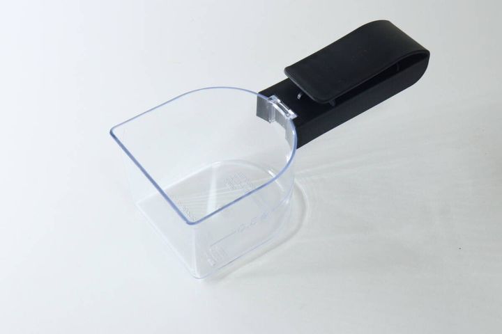 斜め上から見た透明な計量カップと黒いクリップ