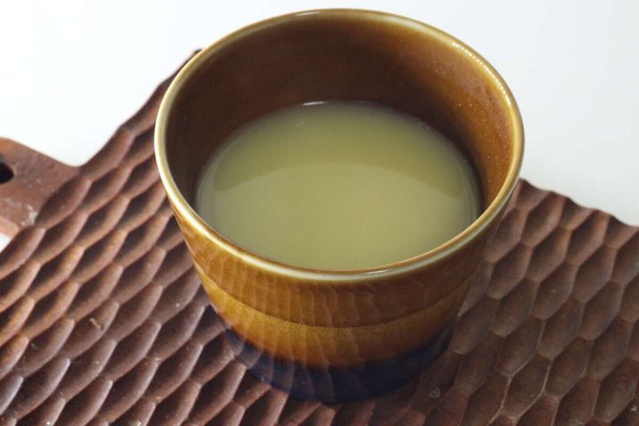 茶色のカップに入ったコーンポタージュが木製のコースターに乗っている