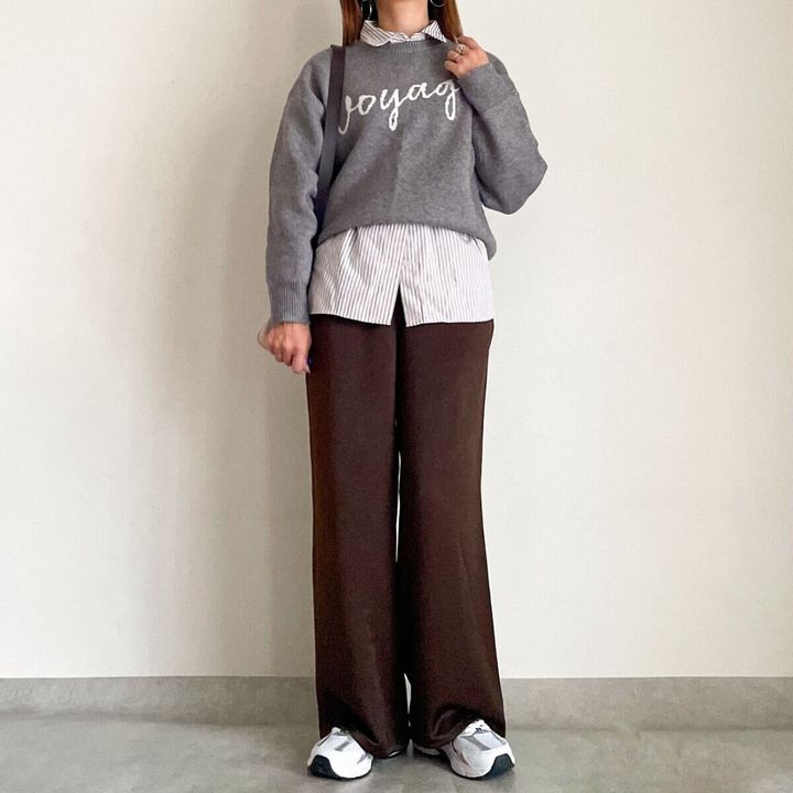 ストライプシャツにグレーのロゴニットを重ね着した、ハンサムなサテンパンツコーデ