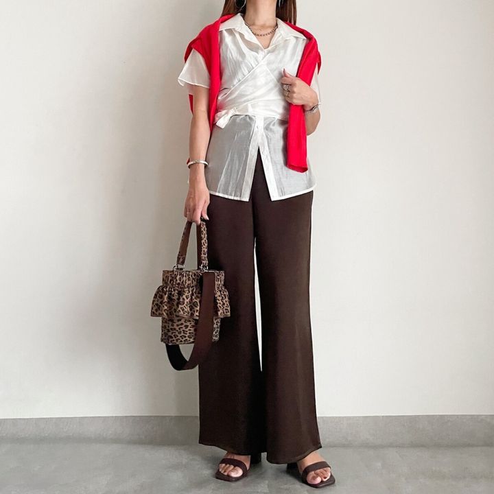 白いシアーシャツと赤いカーディガンを羽織ったサテンパンツの異素材ミックスコーデ