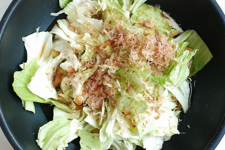 フライパンにキャベツ、厚揚げ、削り節、調味料が入っている様子