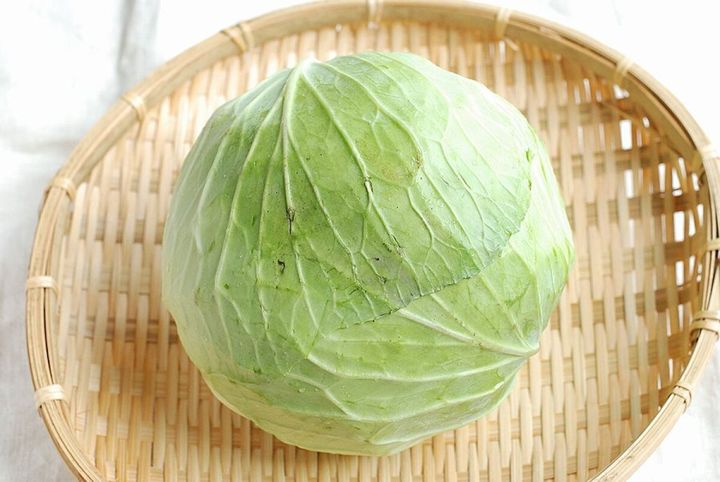 竹ざるの上に置かれた丸ごとの新鮮なキャベツ