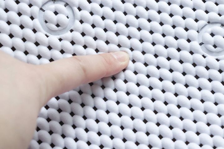 白い浴槽マットの表面を指で押して厚みを確認している
