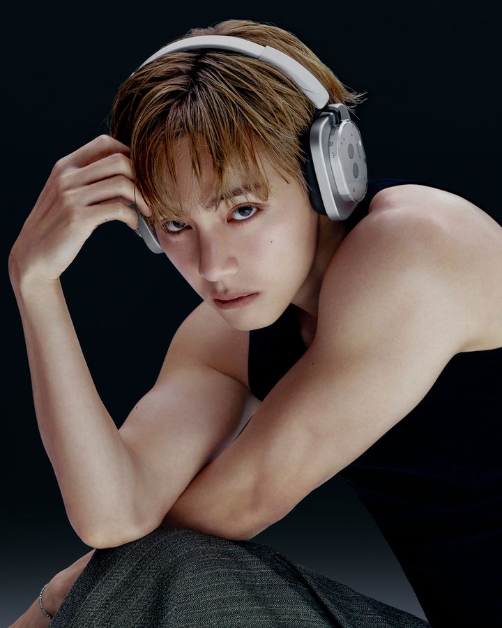 ノースリーブ姿で腕を組み、Headphone (1) Proを着けてこちらを見つめるテテ