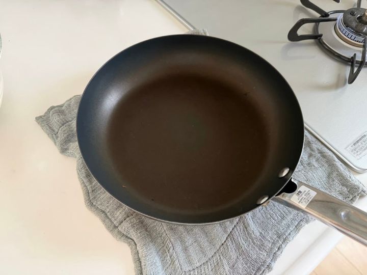 温めたフライパンを濡れ布巾の上に置く様子