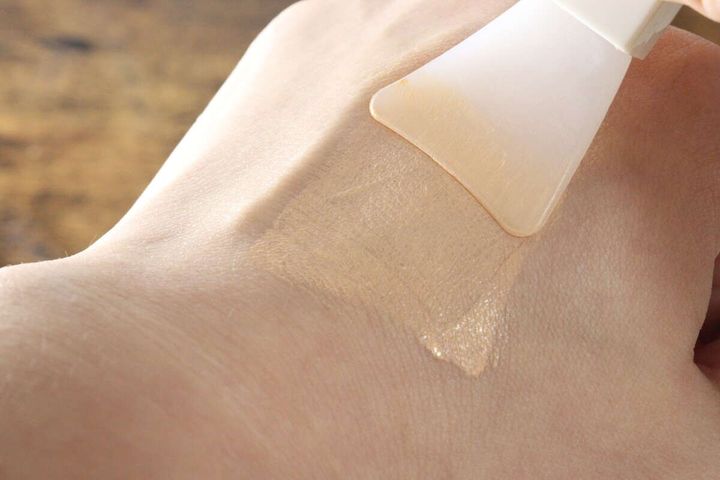 手の甲にファンデーションを白いミニスパチュラで薄く伸ばしている