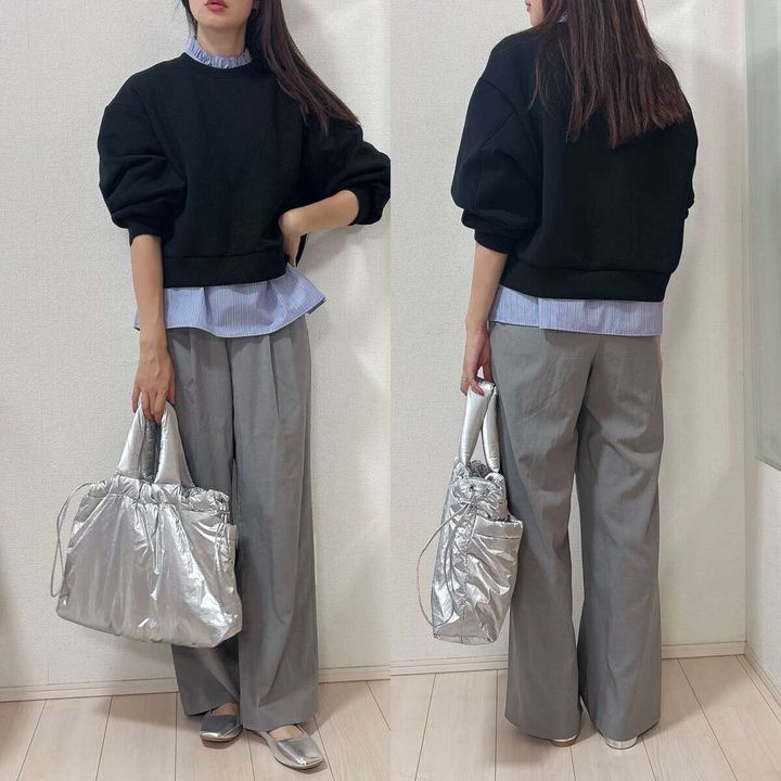 青いブラウスに黒スウェットを重ね着しシルバーバッグを持つ女性