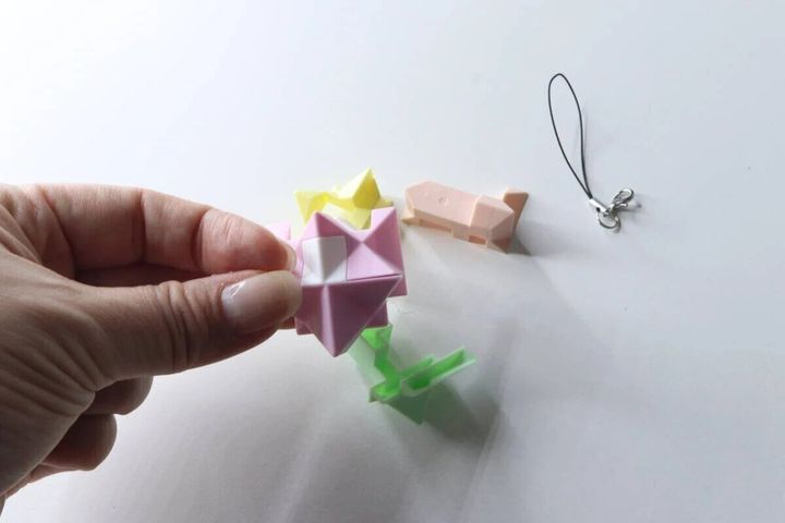手でパステルカラーの星形パズルキーホルダーを組み立てている途中