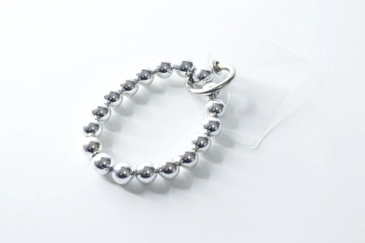 白い背景に置かれたシルバーの玉が連なるブレスレット風スマホストラップ