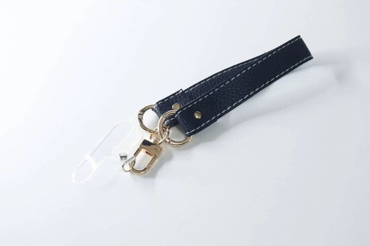 白い背景に置かれた黒い合皮素材のワイドモバイルストラップ