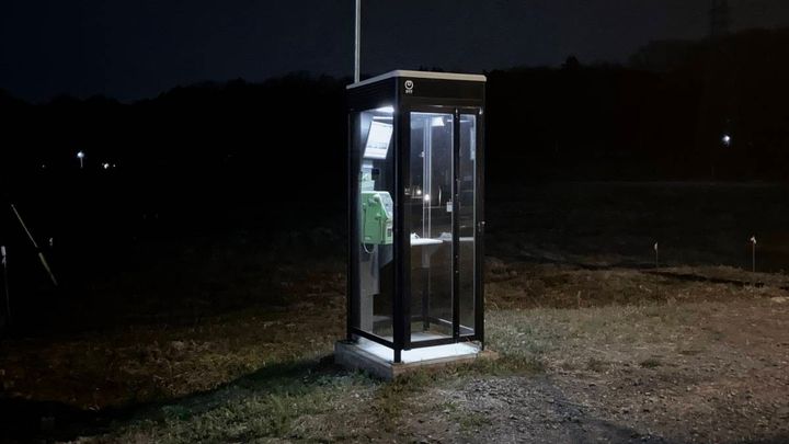 暗い夜道にぽつんと立つ、明かりのついた公衆電話ボックス。