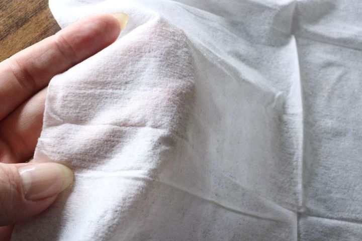 女性の指でウェットシートの厚みと質感を確かめている