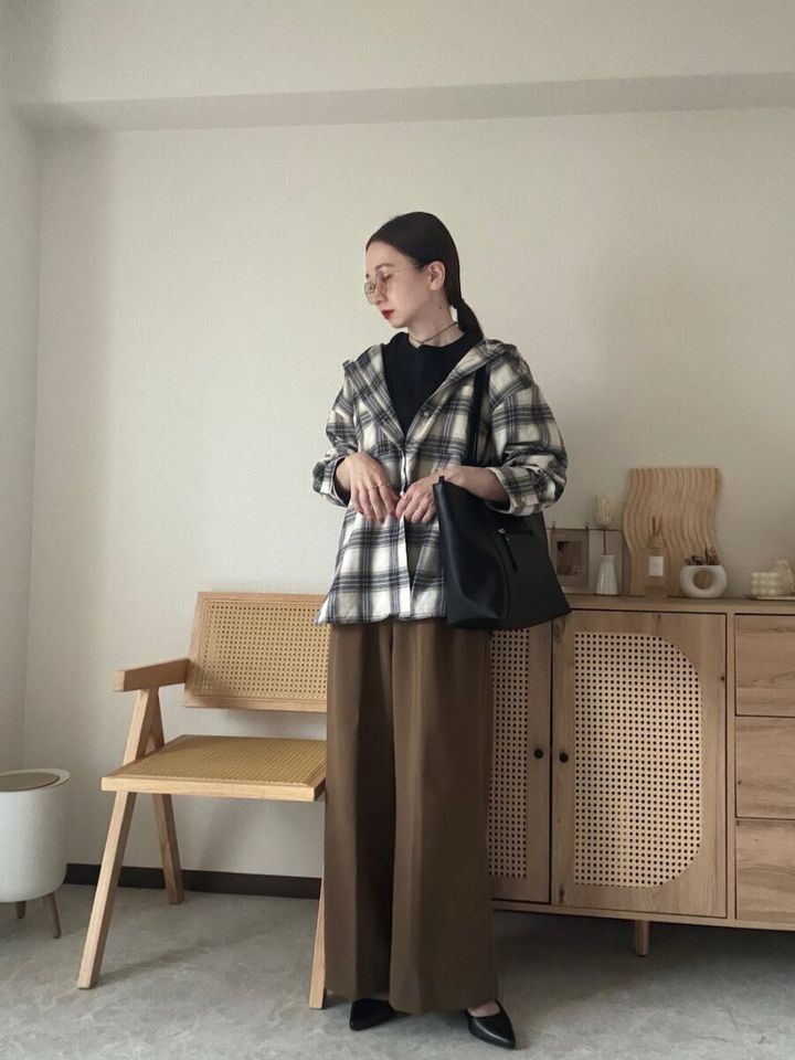 白いチェック柄フードシャツとブラウンワイドパンツの女性