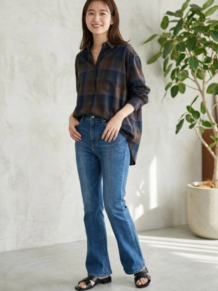 ブラウンとネイビーのチェックシャツをデニムにインした女性