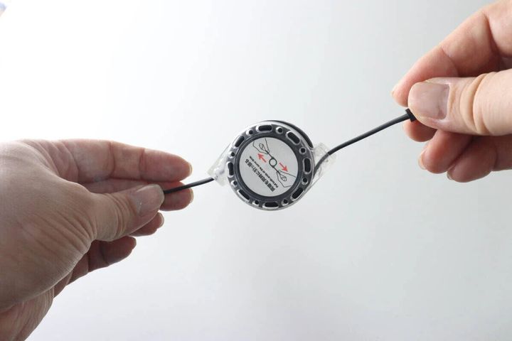 両手でダイソーのリール式充電ケーブルを引っ張って伸ばしている様子