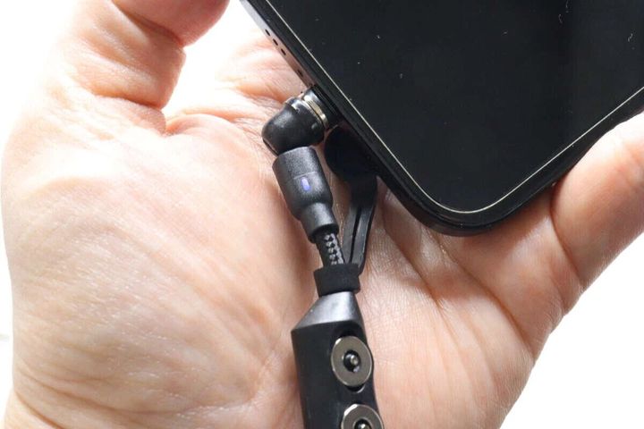 手で持ったスマートフォンにマグネット式充電ケーブルの端子を接続している様子