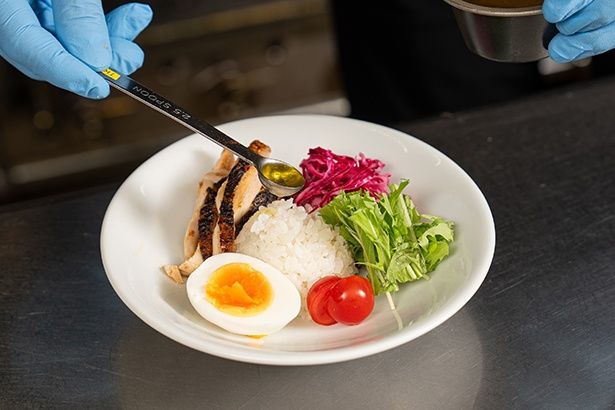 具材の皿の中央にはミニライスも盛られる。かけているのはレモンオイル。野菜は世界各地の店舗で異なり、地場の旬なものを使うという
