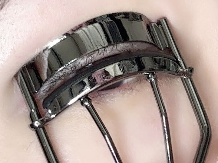 ビューラーでまつ毛の根元をしっかりと挟んでいる目元のアップ