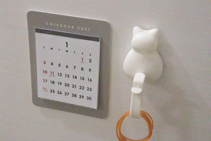 マグネットカレンダーが冷蔵庫に貼られ、隣に猫のフックがある