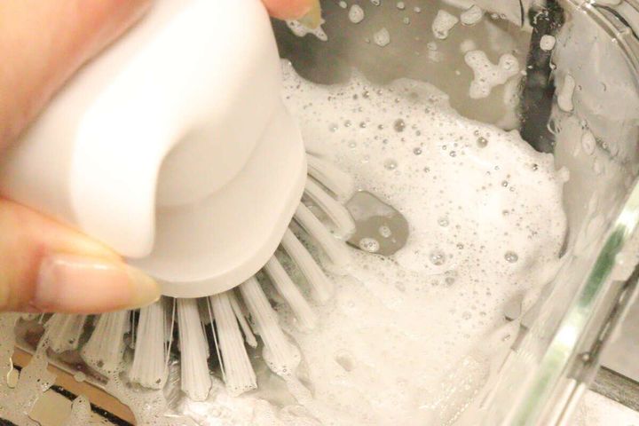 泡立ったシンクで、ハンドキッチンブラシを使って食器を洗っている様子