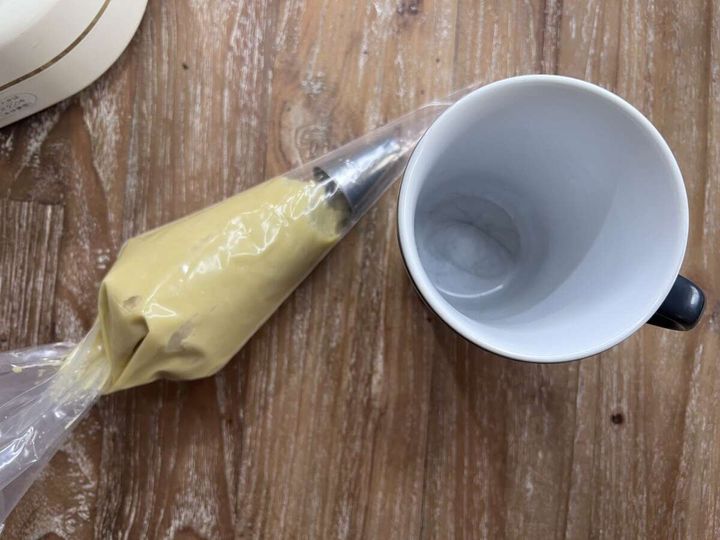 絞り口をセットした絞り袋に焼き芋クリームが詰められ、隣に白いマグカップが置かれている