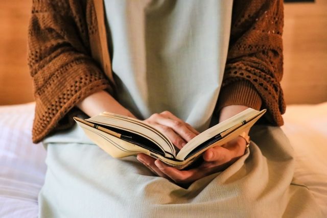 夕方 ベッドに腰掛けて読書する人