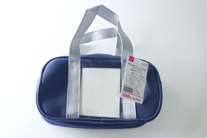 ネイビーの取手付ペンケースと商品タグ