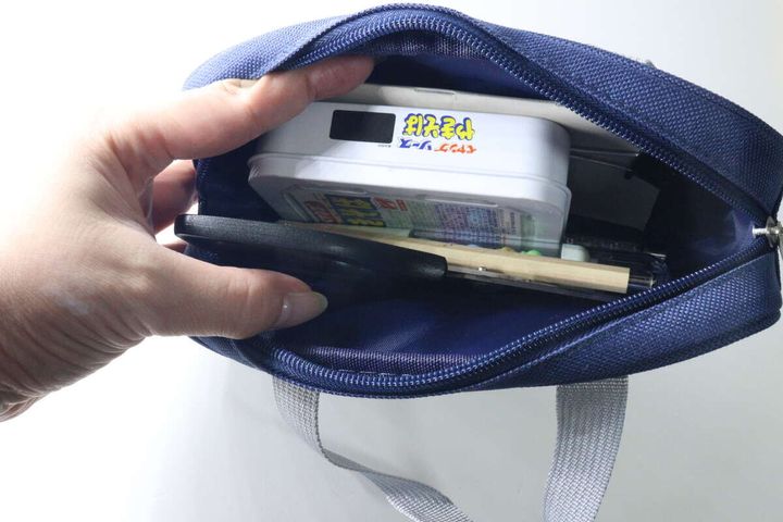 ペンケースのファスナーを開け文具を入れている