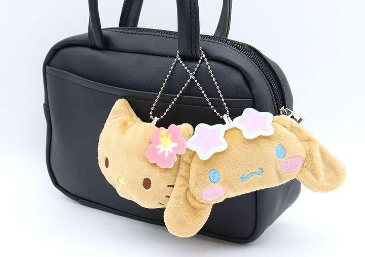 黒いハンドバッグに付けられた、日焼けハローキティとシナモロールのチャーム