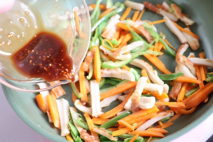 にんじん、ピーマン、ちくわを調味料と炒める様子
