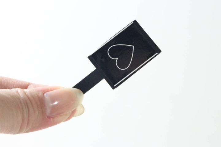 指で持った黒いマグネットの表側、白いハートマーク