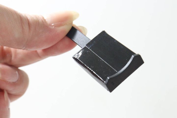 指で持った黒いマグネットの裏側、爪にフィットするカーブ