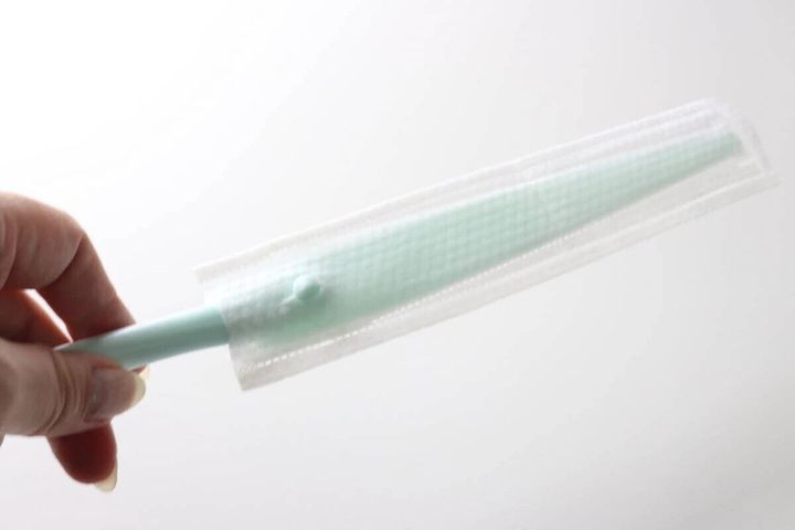 手でエアコンの防カビスキマワイパーに防カビシートを装着している様子