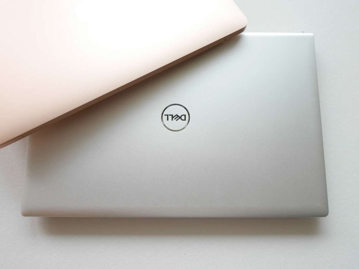 銀色のDELL製ノートパソコンとピンク色のノートパソコンが重なっている