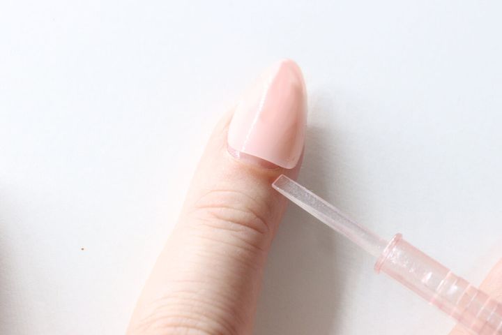ネイルチップと指の隙間にスティックのヘラ状先端を差し込んでいる