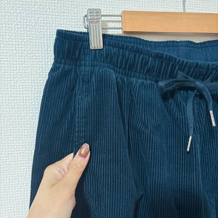 女性が黒いコーデュロイパンツの生地を指で触っているアップ