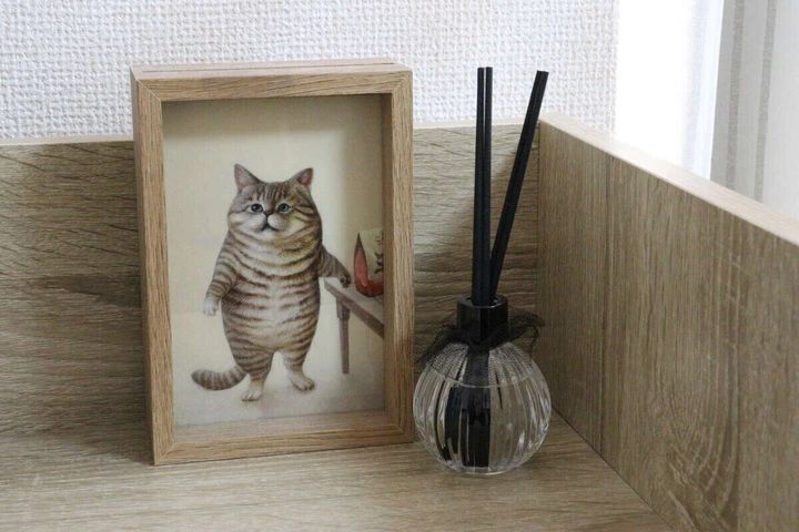 猫の絵のフレームと並んで棚に置かれたディフューザー