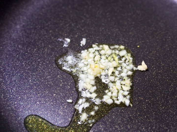 フライパンにオリーブオイルとみじん切りにんにくを入れ弱火で炒めている