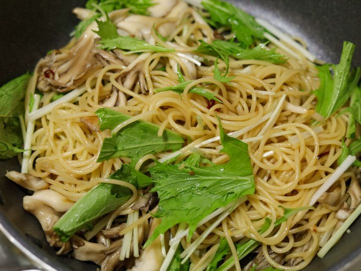 パスタとまいたけに水菜を加えて全体を混ぜ合わせている