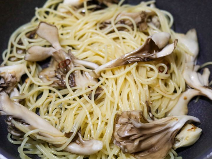 茹で上がったスパゲッティをまいたけと一緒にフライパンで混ぜている