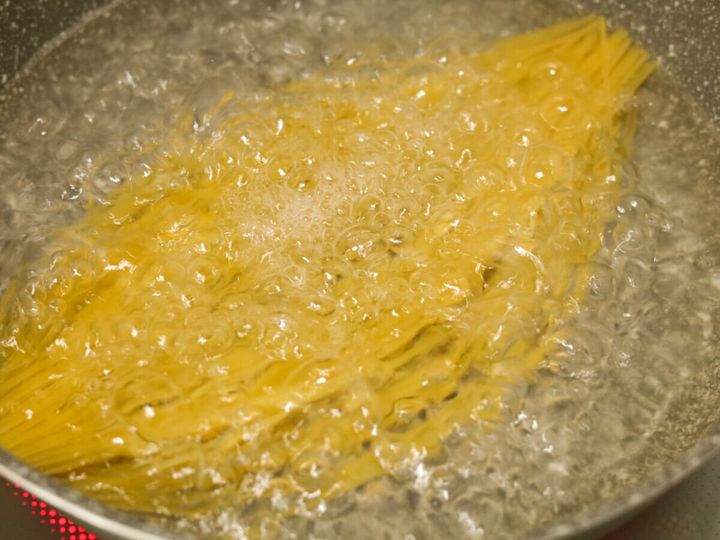鍋で沸騰したお湯の中でスパゲッティを茹でている様子