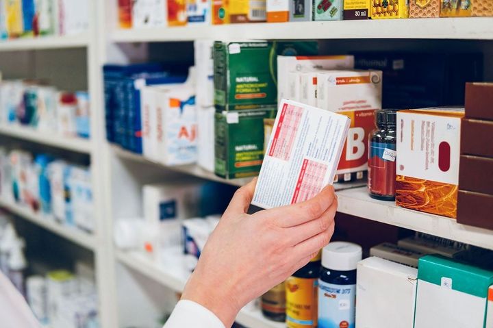 薬局の棚に薬を並べる薬剤師の手元