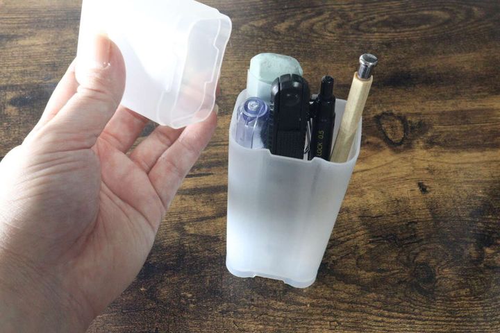 ペンや消しゴムが入ったペンケーススタンドの蓋を開ける手元