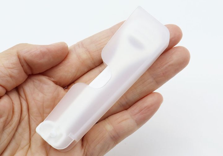 折りたたんだ状態の白い舌クリーナーを手のひらに乗せている