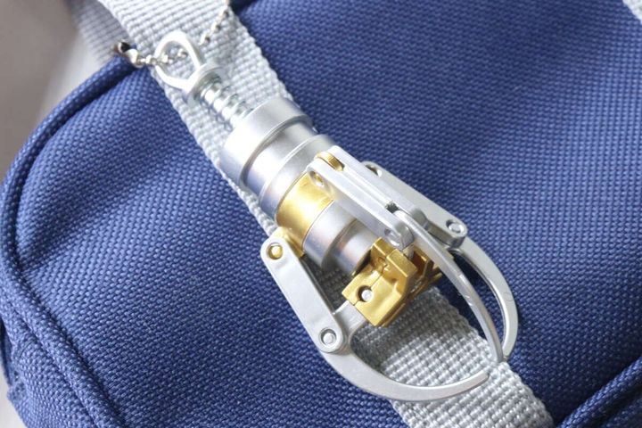 キャッチャーアームキーホルダーが紺色のカバンに取り付けられている