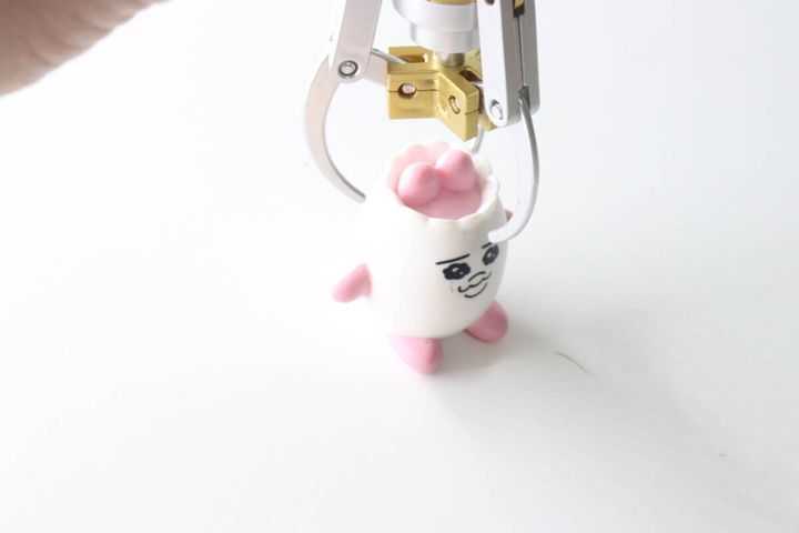 キャッチャーアームキーホルダーが白いマスコットを掴もうとしている