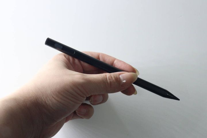 女性が黒い充電式タッチペンを手に持ち、ペン先を指している様子