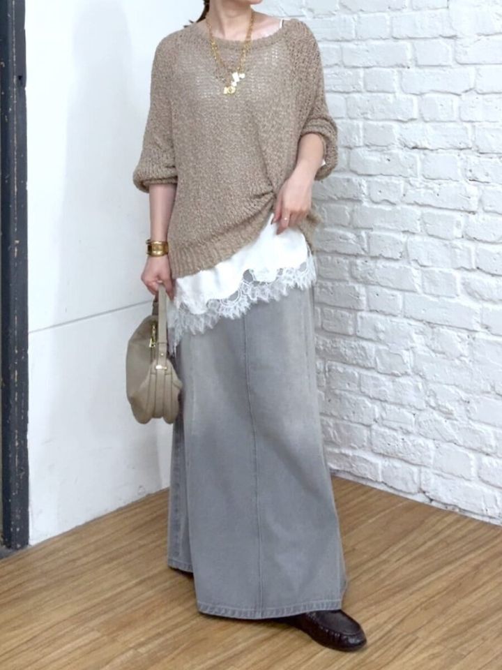 ベージュニットとグレーデニムスカートを着た女性